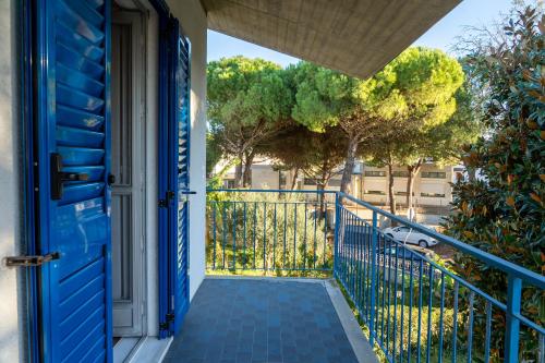 una porta blu che conduce a un balcone con alberi di Lido Adriano Garden House a Lido Adriano