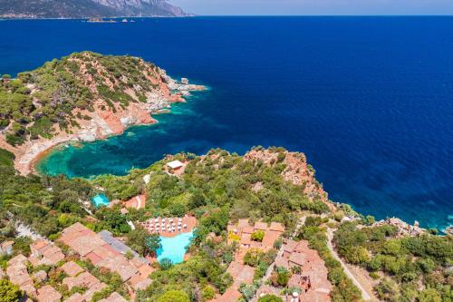 Arbatax Park Resort - Borgo Cala Moresca في ارباتاكس: اطلالة جوية على جزيرة ذات ماء ازرق