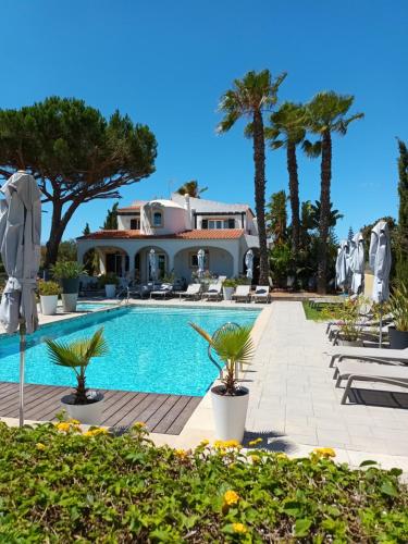 una villa con piscina y palmeras en Casa Bela Moura, Boutique Hotel & Wine, en Porches