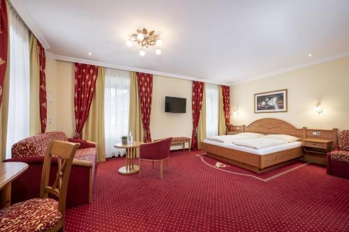 Ferienhotel Gasthof zur Post في أونتيرتاورين: غرفة فندق بها سرير وطاولة وكراسي