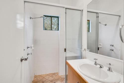 a white bathroom with a sink and a shower at Tree Elle Retreat in Bow Bridge