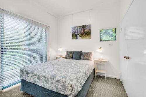 a white bedroom with a bed and a window at Tree Elle Retreat in Bow Bridge