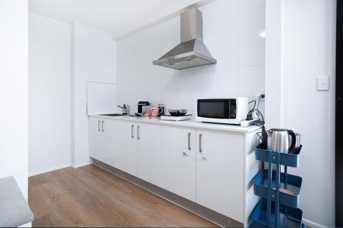a kitchen with white cabinets and a microwave at 3BR Cozy Sunnybank Hills Home in Brisbane