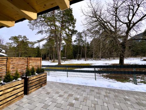 Un pabellón con una valla y un estanque con nieve. en LechHuamat, en Weissenbach am Lech