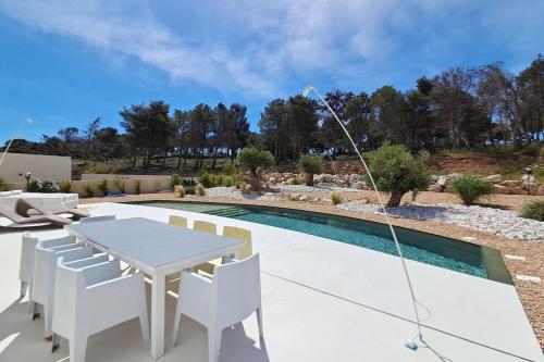 een terras met een tafel en stoelen naast een zwembad bij Casa Bianca - Villa d'architecte avec piscine in Leucate