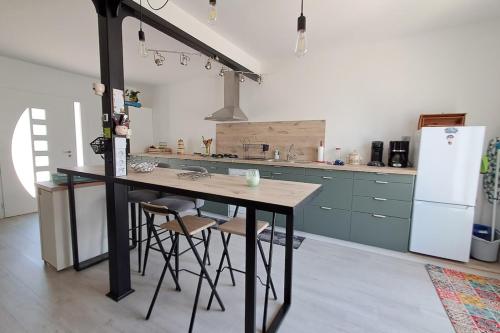 a kitchen with a counter with stools and a refrigerator at L'évasion des Corbières in Portel-des-Corbières