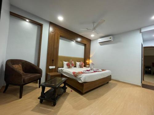 a bedroom with a bed and a chair in it at Hotel Alento in Jamnagar