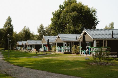 a row of cottages with a playground at Recreatiepark de Vossenburcht IJhorst in IJhorst