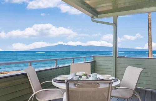 a table and chairs on a balcony overlooking the ocean at Coastal Paradise Condo with Panoramic Ocean Views in Kahana