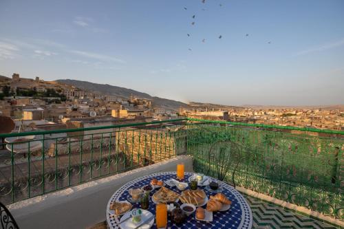 een tafel op een balkon met uitzicht op de stad bij Dar El Kendil in Fès