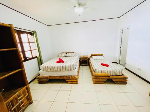 two beds in a room with white tile floors at Oceanfront Scuba Villa in Moalboal