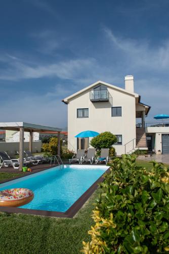 a villa with a swimming pool in front of a house at Viana Fishers House - Pool & Beach ! in Viana do Castelo