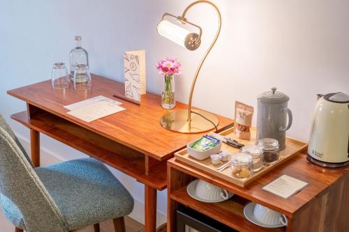 a desk with a lamp and a vase of flowers on it at Pergola Boutique Hotel in Cascais