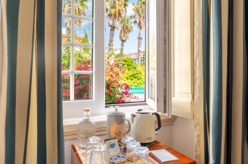 a table with a coffee maker and two windows at Pergola Boutique Hotel in Cascais