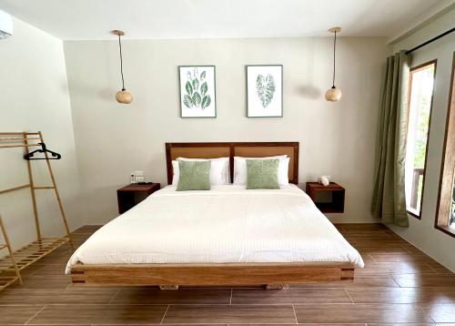 una camera da letto con un letto con lenzuola bianche e cuscini verdi di Aulea Siargao a General Luna