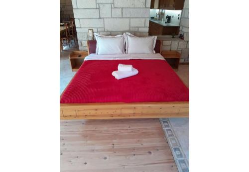 a bed with a red blanket on top of it at Tsarouxi village 1 in Drakótrypa