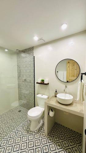 a bathroom with a toilet and a sink and a mirror at Aulea Siargao in General Luna