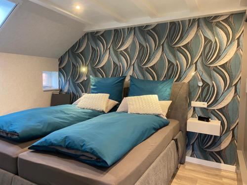 Ferienwohnung im Gulfhof, 65269 في Moormerland: غرفة نوم بسريرين مع وسائد زرقاء وجدار
