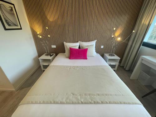 a bedroom with a large white bed with a pink pillow at Hôtel les Coulisses in Forbach