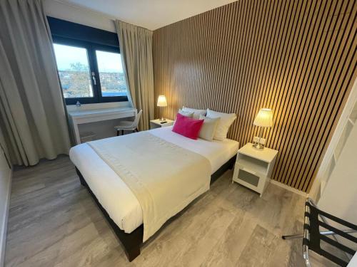a bedroom with a large white bed with a pink pillow at Hôtel les Coulisses in Forbach