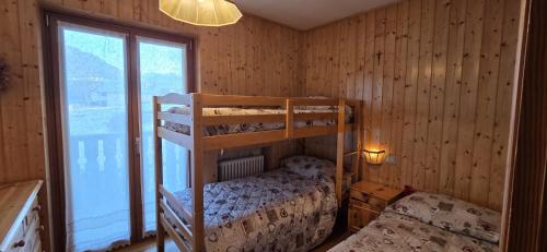 a bedroom with two bunk beds and a window at Casa Vaiolet in Pozza di Fassa
