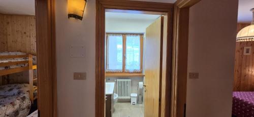 a room with a door open to a bedroom with a window at Casa Vaiolet in Pozza di Fassa