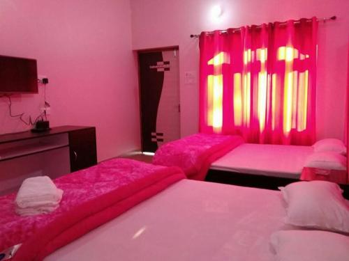 zwei Betten in einem rosa Zimmer mit rosa Vorhängen in der Unterkunft Treat Hotel And Restaurant in Naimishāranya