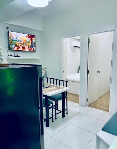 a kitchen with a dining table and a tv on the wall at Naga City River View 2BR UB Apartment in Naga