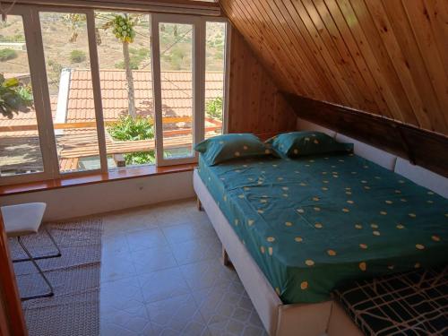 Paraiso das ilhas في Ribeirão Chiqueiro: غرفة نوم مع سرير مع لحاف أخضر ونوافذ