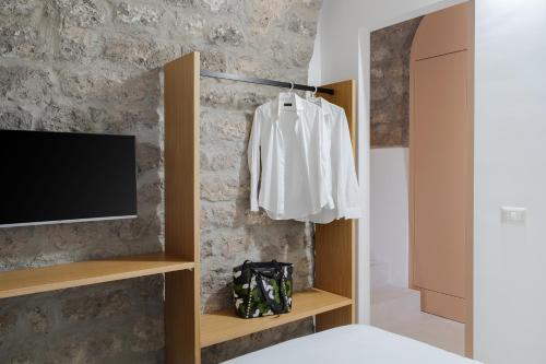 a bedroom with a tv and a white shirt hanging on a wall at L'Appoggio in Castellammare di Stabia