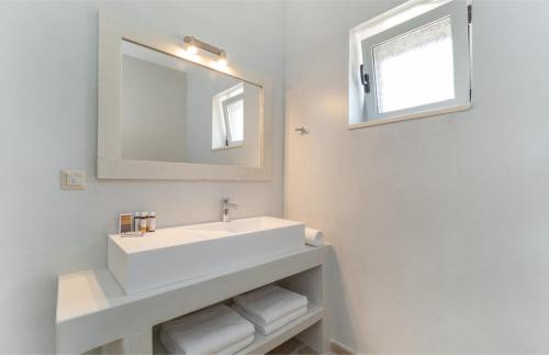 une salle de bains blanche avec un lavabo et un miroir dans l'établissement Villa Moundela, à Katsimátika