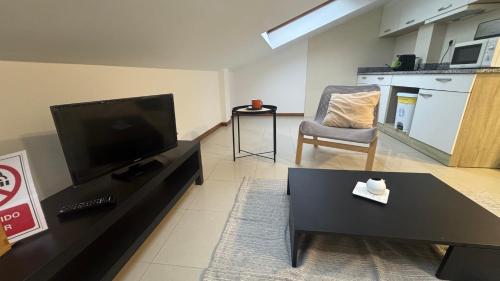 Una sala de estar con un televisor de pantalla plana y una silla. en Atico Finisterre, en Finisterre