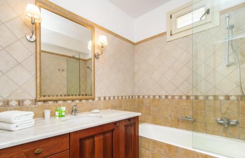 een badkamer met een wastafel, een bad en een spiegel bij Villa Athina in Ayios Nikitas