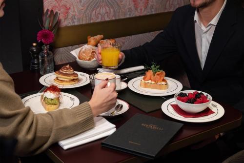 two people sitting at a table with food and drinks at Palazzo Touring Club Milan, A Radisson Collection Hotel in Milan