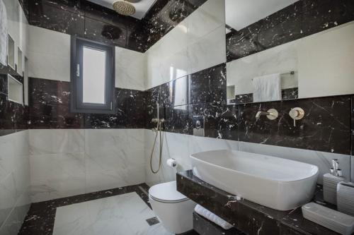 a black and white bathroom with a sink and a toilet at Villa Stellina in Karavádhos