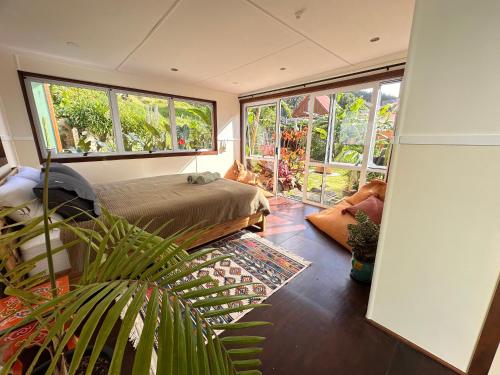 een slaapkamer met een bed en grote ramen bij Pandora Cottage Beachfront in Raglan