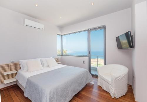 a white bedroom with a bed and a large window at Villa Isidora in Sitia