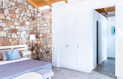 Loutsa Waterside في فاثي: غرفة نوم بحائط حجري وسرير