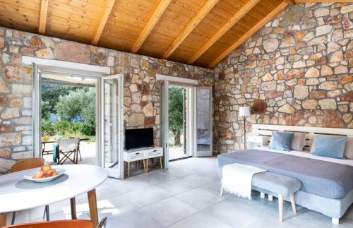 Loutsa Waterside في فاثي: غرفة نوم بسرير وجدار حجري