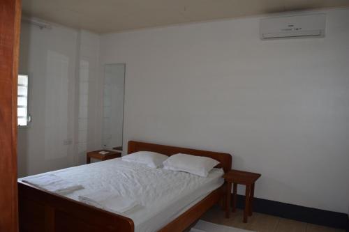1 Schlafzimmer mit einem Bett mit weißer Bettwäsche und 2 Kissen in der Unterkunft Klein-kronenburg Bakkershuisje in Paramaribo