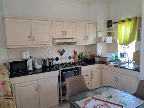 Triplex - Suite parentale في غراند غايوب: مطبخ صغير مع دواليب بيضاء وطاولة مع طاولة