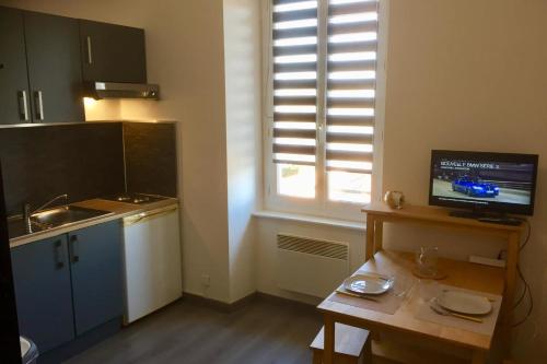 eine kleine Küche mit Tisch und Fenster in der Unterkunft Gîte Studio Les Oliviers in Narbonne