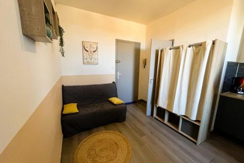 ein kleines Wohnzimmer mit einem Sofa und einem Fenster in der Unterkunft Gîte Studio Les Oliviers in Narbonne