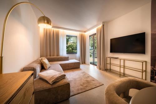 een woonkamer met een bank en een flatscreen-tv bij goldfinger + suites in Lana