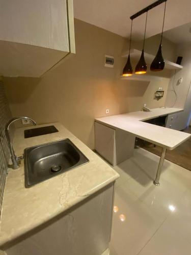 a kitchen with a sink and a counter with pendant lights at Studentpark apartment by RD in Yogyakarta