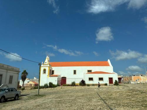 a person standing in front of a white church at A casa do amor in Vila do Maio