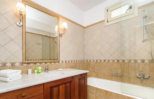 een badkamer met een wastafel, een bad en een spiegel bij Villa Valia in Ayios Nikitas