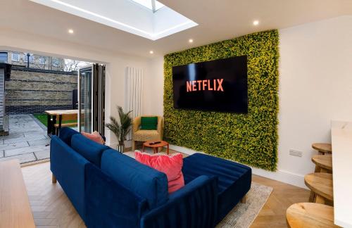 a living room with a blue couch and a tv on a wall at Abbotsford House sleeps 8 in York