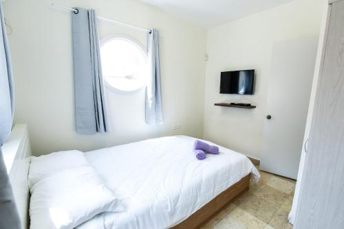 um quarto com uma cama branca e uma almofada roxa em Villa Or - Heated Pool em Eilat