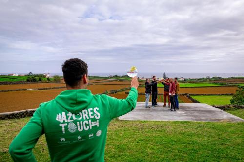 a man in a green sweatshirt holding a frisbee at Casa dos Calços in Angra do Heroísmo